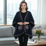 Woman wearing a black poncho with purple accents in a modern living room.