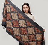 Woman holding a decorative scarf with intricate patterns on a plain background