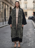 Woman wearing a long, patterned coat on a city street.