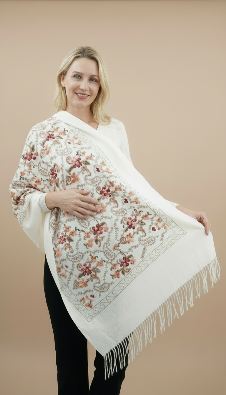 Woman wearing a white floral embroidered shawl on a plain background